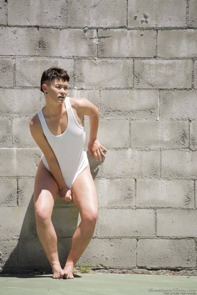 Short haired dyke Jiz Lee strips for nude poses against a cinder block wall - #5