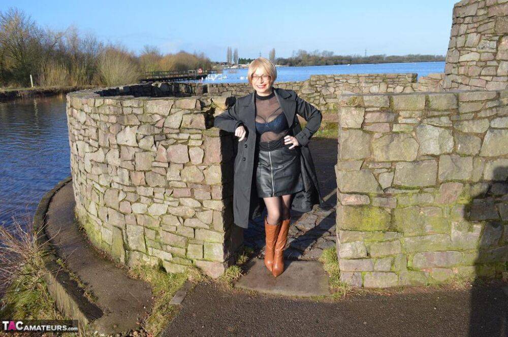 Mature blonde Barby Slut exposes her tits and twat in leather coat by a river - #3