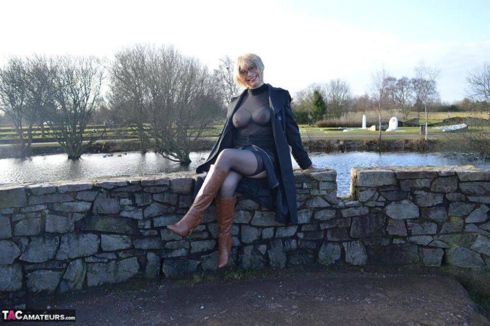 Mature blonde Barby Slut exposes her tits and twat in leather coat by a river - #14