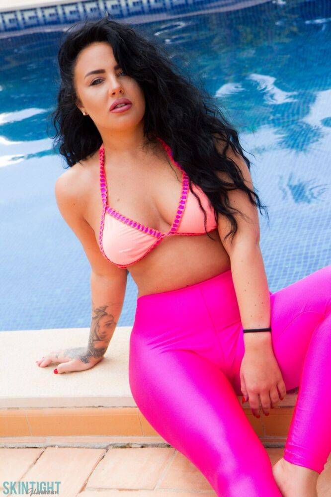 Glamour model Olivia Paige slips pink leggings over bikini bottoms by a pool - #10