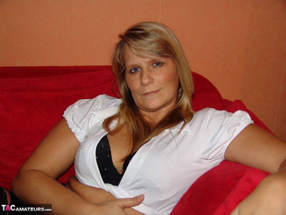 Blonde amateur Sweet Susi strips down to her stockings while on a red sofa | Photo: 1325582