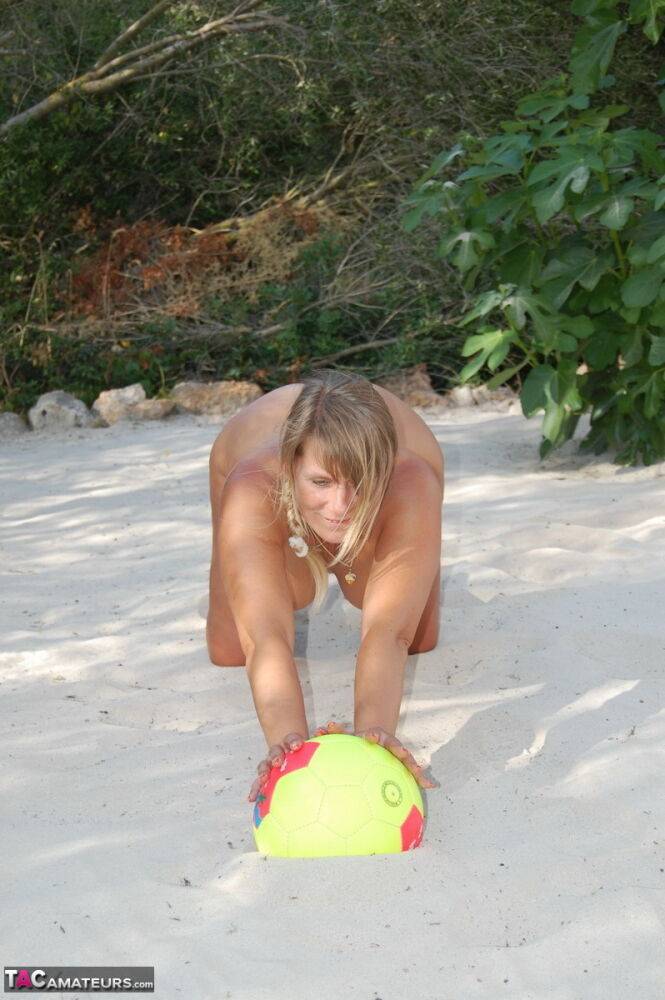 Mature woman Sweet Susi models totally naked on a patch of sand in a backyard | Photo: 1326516