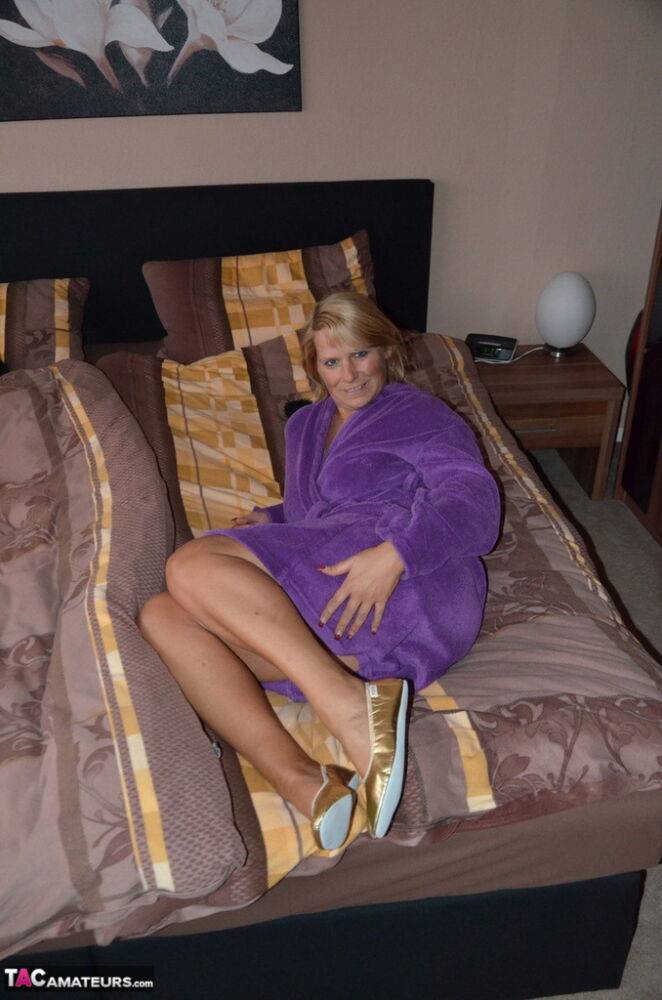 Mature blonde Sweet Susi removes her housecoat for nude poses on her bed | Photo: 1328095