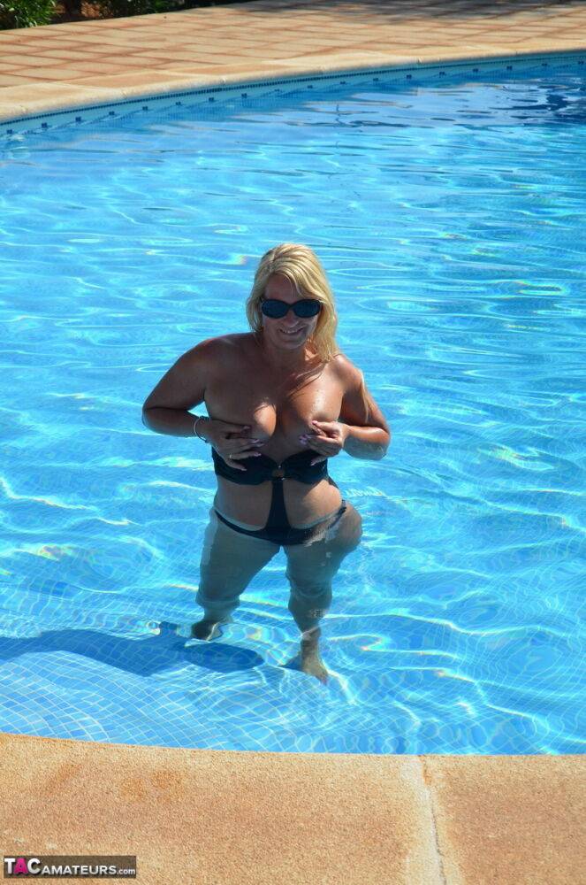 Middle-aged blonde Sweet Susi frees her tits & pussy from a swimsuit by a pool - #12