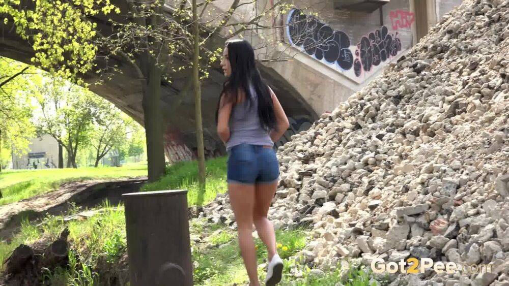 Dark haired traveler Lexi looks for a place to pee and pisses under a bridge - #5