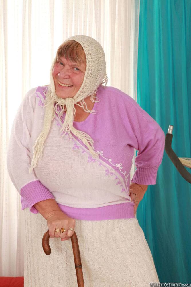 Old granny Sara G in skirt & boots sheds sweater to show huge tits in bra - #1