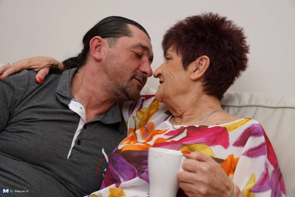 Old woman kisses her man friend during foreplay action on a couch - #4