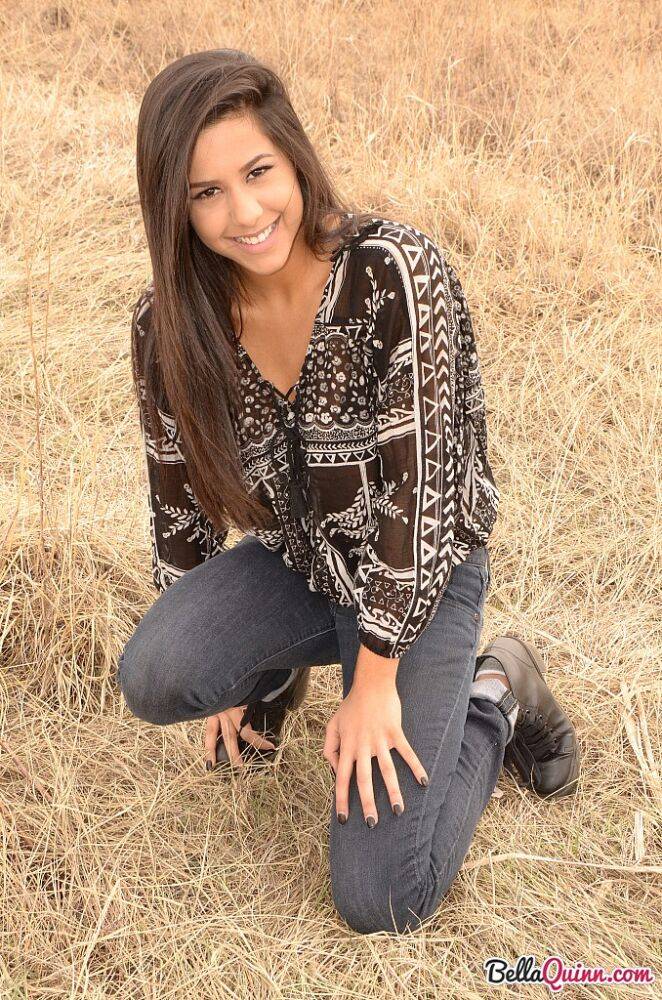 Latina girl Bella Quinn models in a field wearing a bra and jeans | Photo: 1862699