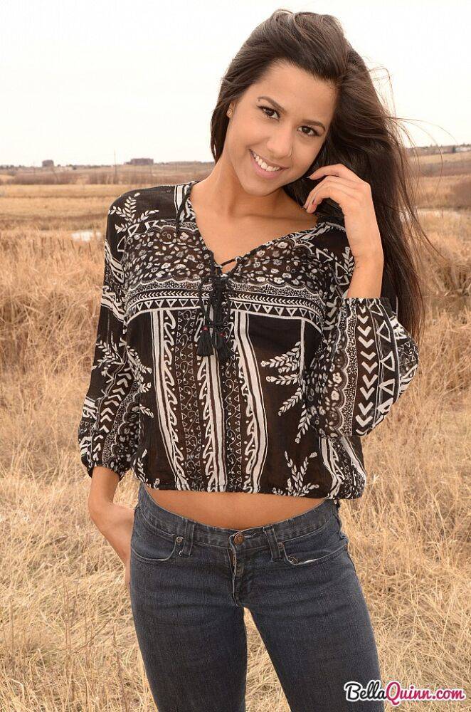 Latina girl Bella Quinn models in a field wearing a bra and jeans | Photo: 1862652