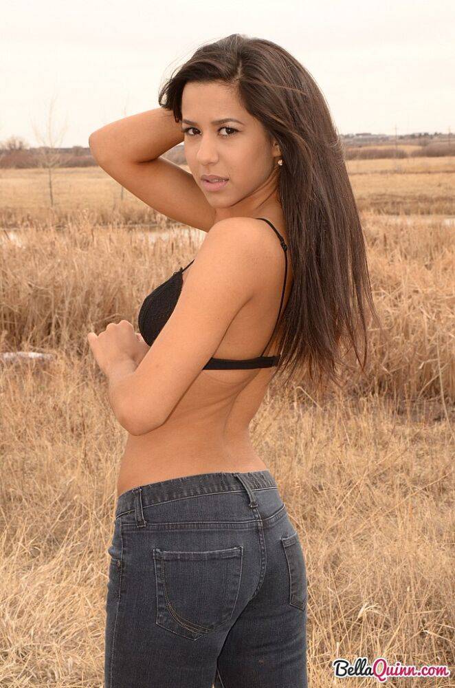 Latina girl Bella Quinn models in a field wearing a bra and jeans | Photo: 1862730