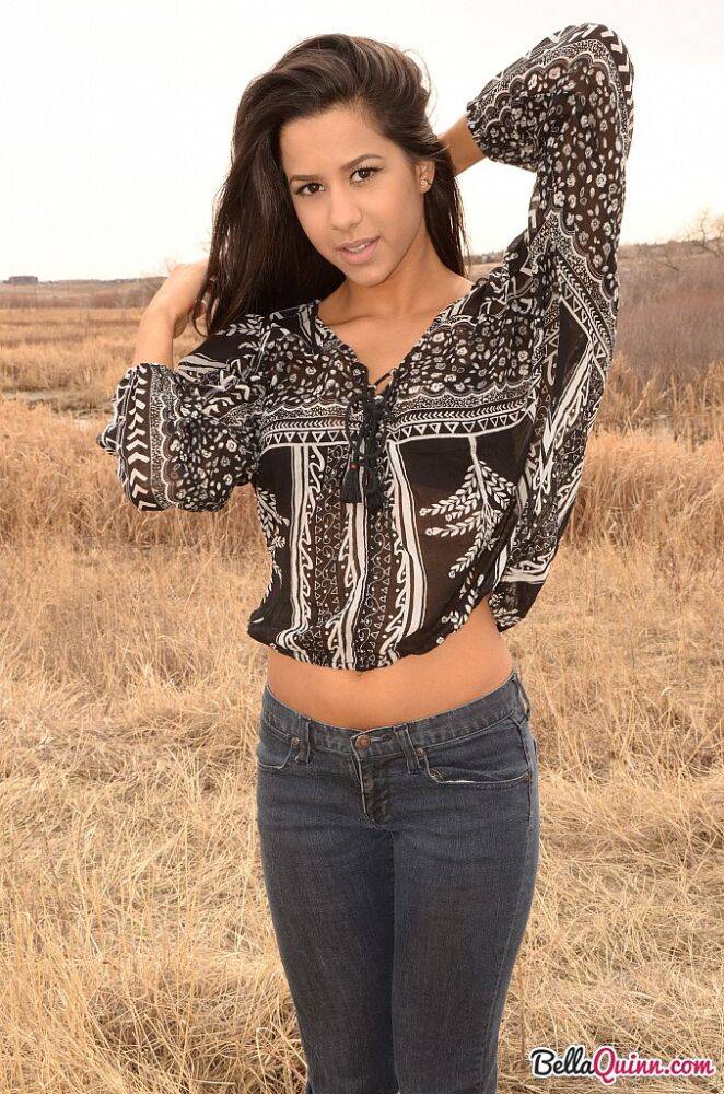 Latina girl Bella Quinn models in a field wearing a bra and jeans | Photo: 1862723