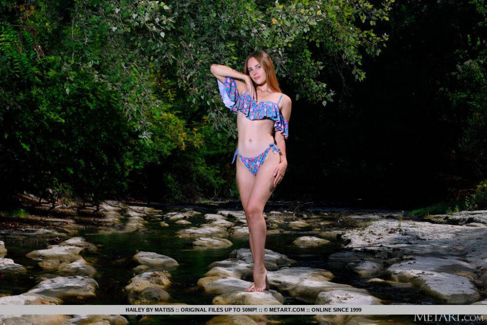 Young redhead Hailey plays with her long hair while naked on rocks in a stream - #6