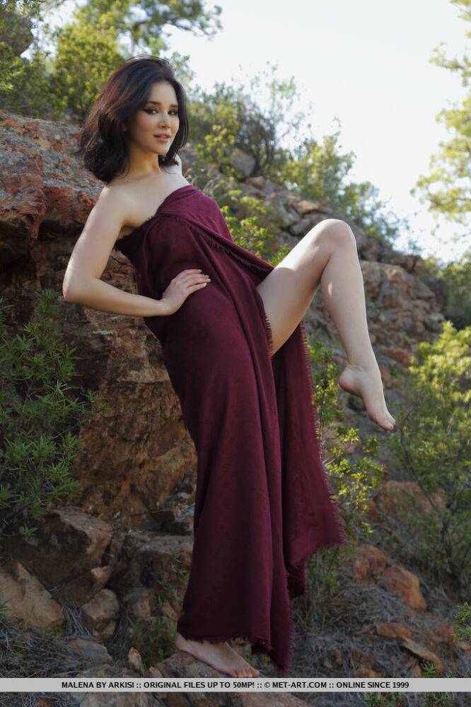 Barefoot teen Malena slips off a long dress to pose nude on a rocky bank - #10