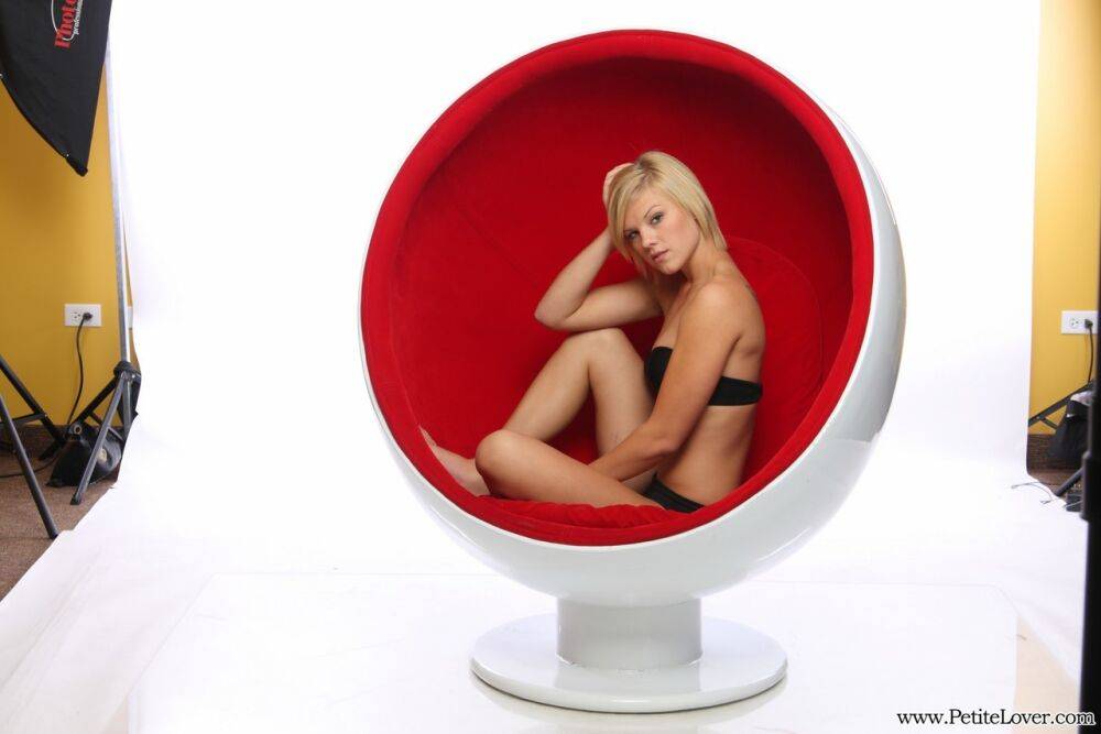 Young blonde girl models in a red chair wearing a black bra and panty set - #13