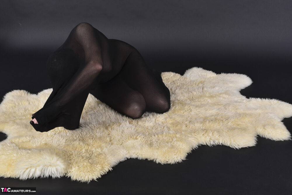 Naked mature woman encases herself in a stocking atop a rug - #10