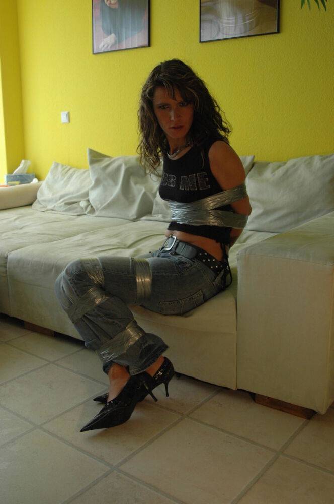 Clothed female is silenced and restrained with duct tape on a sofa - #13