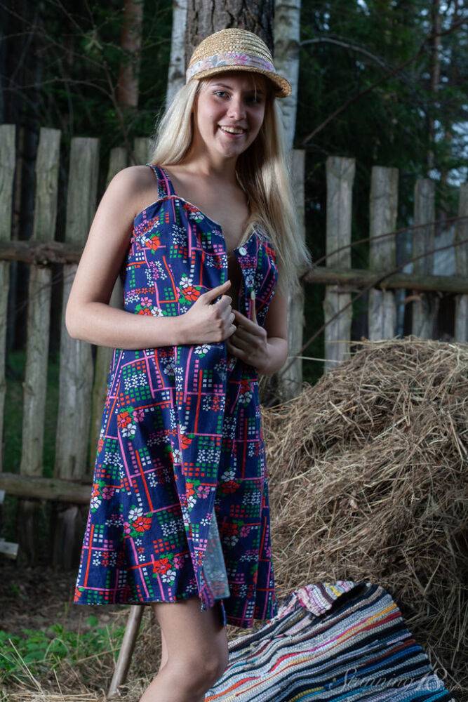 Young blonde Agnes H doffs a dress to get naked on weathered straw in a yard - #9