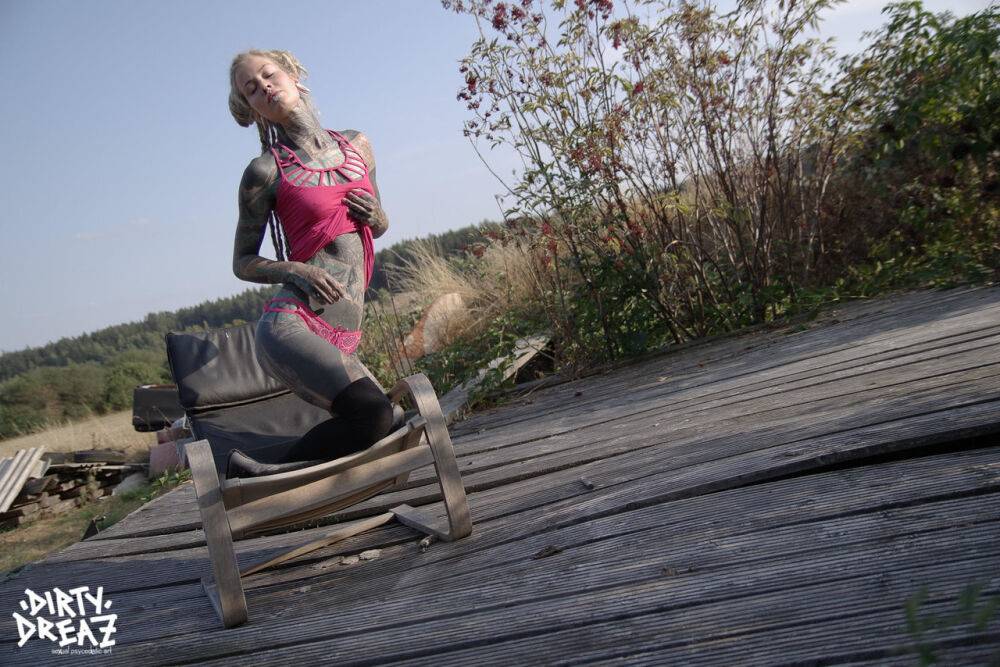 Heavily inked blonde takes off her pink dress on a wooden stage outdoors - #4