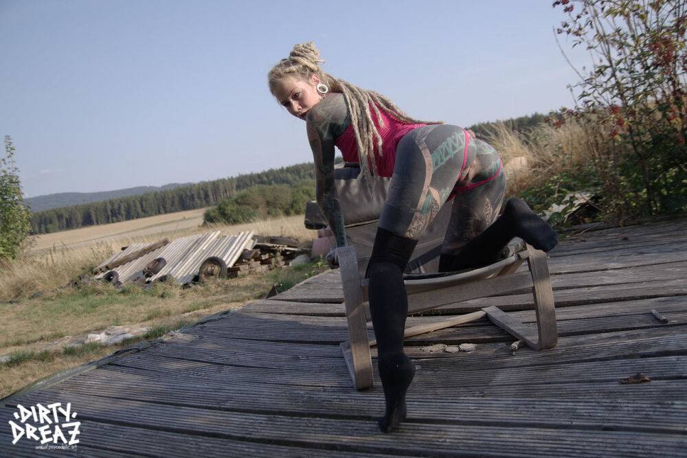 Heavily inked blonde takes off her pink dress on a wooden stage outdoors - #6