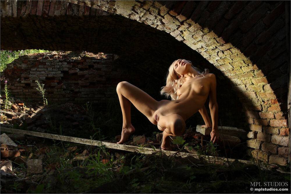 Blonde model strikes confident nude poses beneath a brick overpass - #8