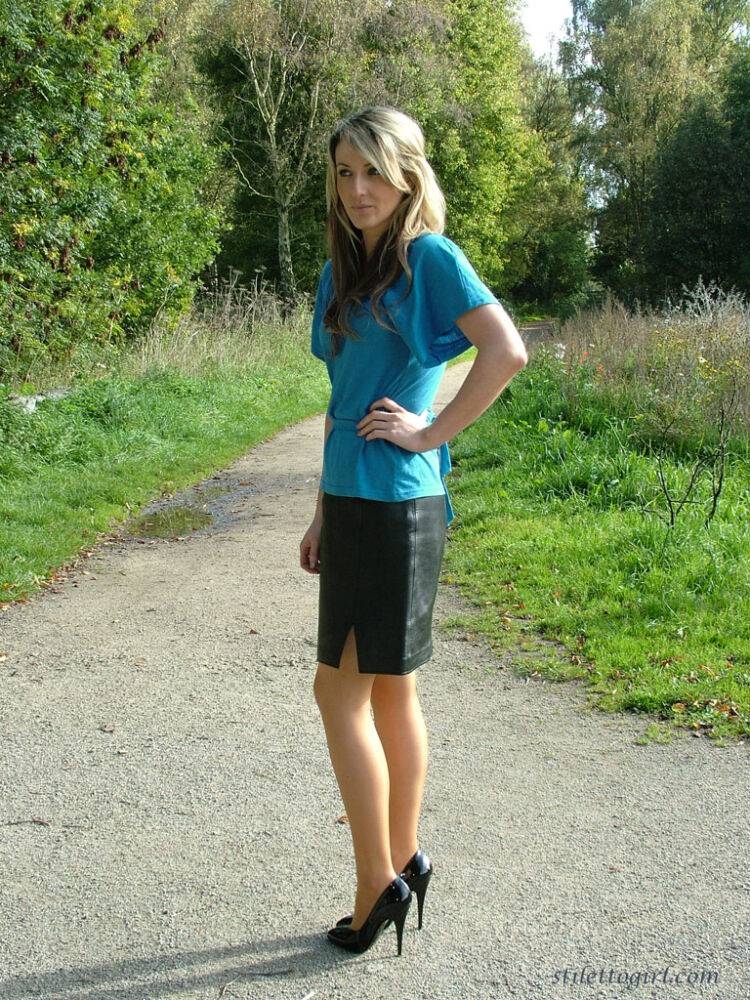 Clothed woman shows off her shapely legs outdoors in a skirt and black pumps - #10