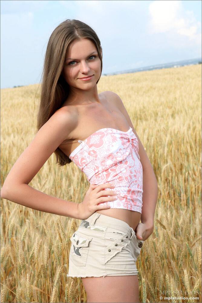 Solo girl twists her hair while standing naked in a field of wheat - #1