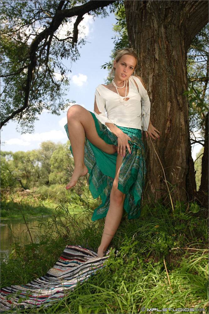 White teen frees her thin body from clothes next to a still river - #11