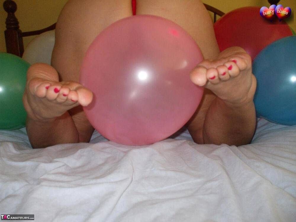 Mature woman Busty Bliss goes topless on her bed while playing with balloons - #14