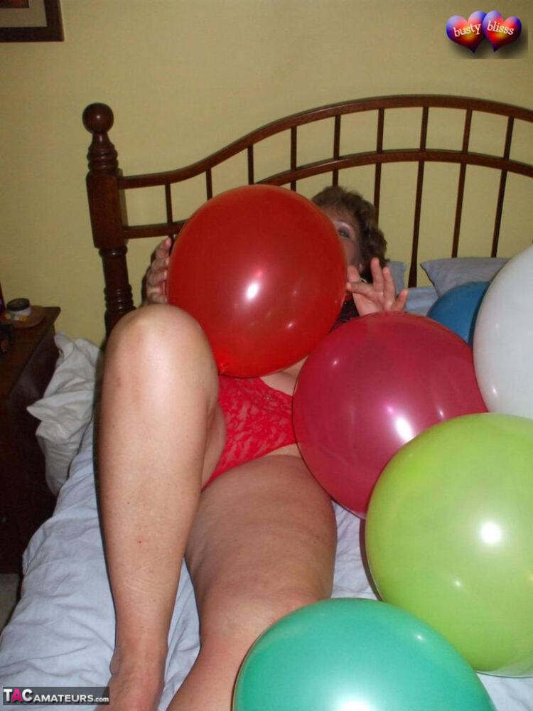 Mature woman Busty Bliss goes topless on her bed while playing with balloons - #16