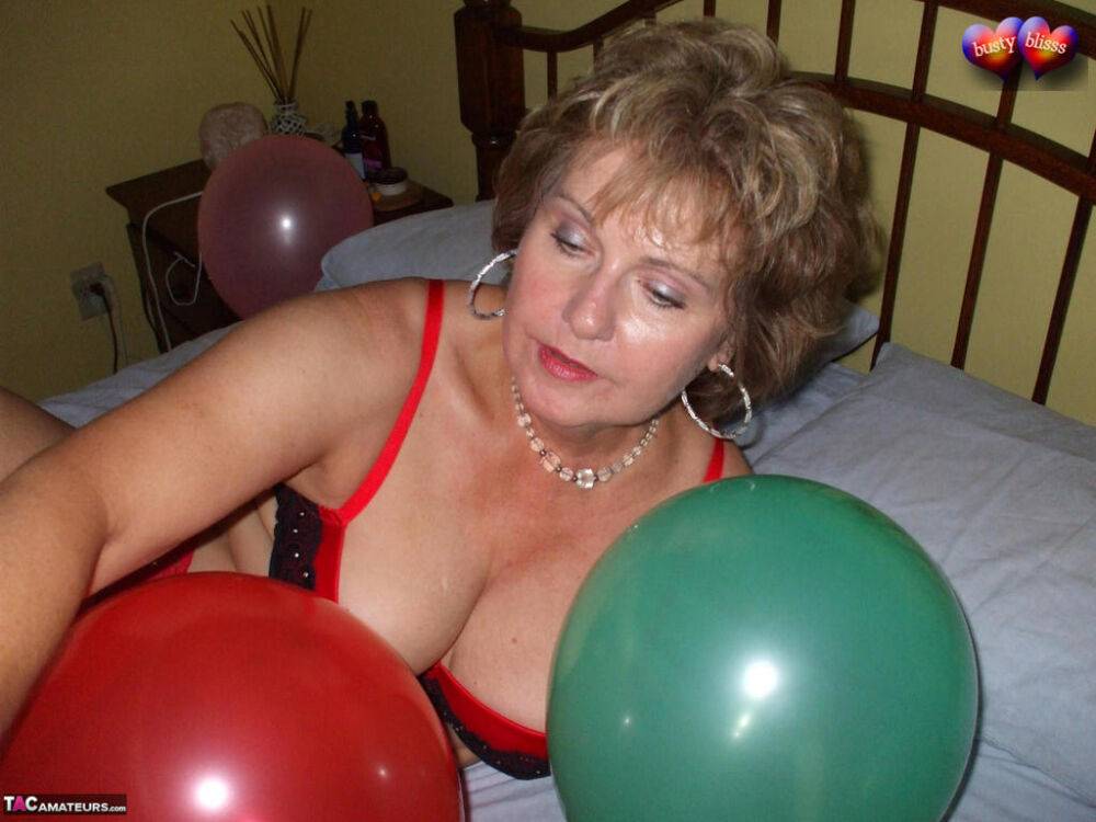 Mature woman Busty Bliss goes topless on her bed while playing with balloons - #8