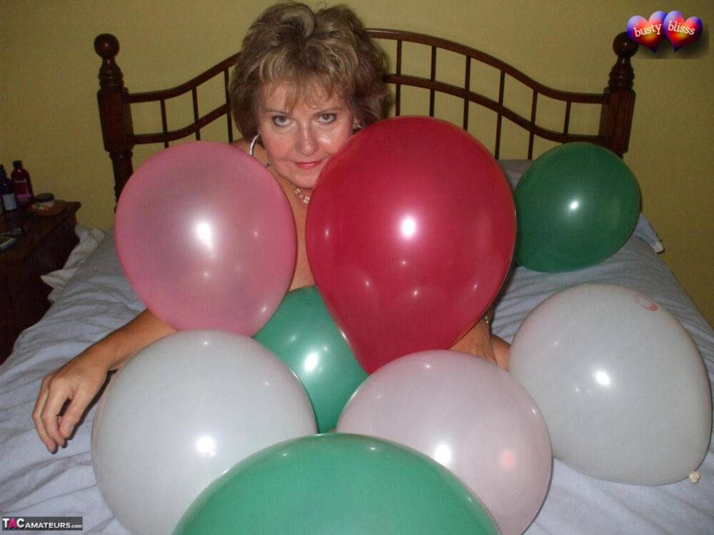 Mature woman Busty Bliss goes topless on her bed while playing with balloons - #10