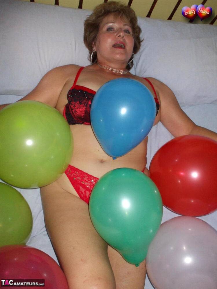 Mature woman Busty Bliss goes topless on her bed while playing with balloons - #6