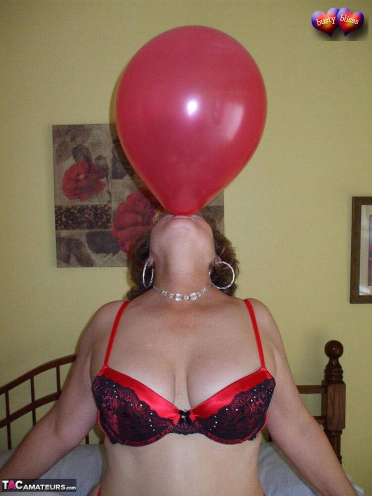 Mature woman Busty Bliss goes topless on her bed while playing with balloons - #9