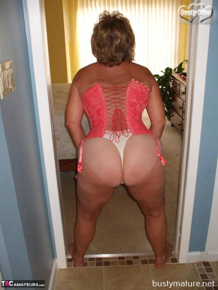 Mature amateur Busty Bliss models a laced up corset and thong in her bare feet - #1