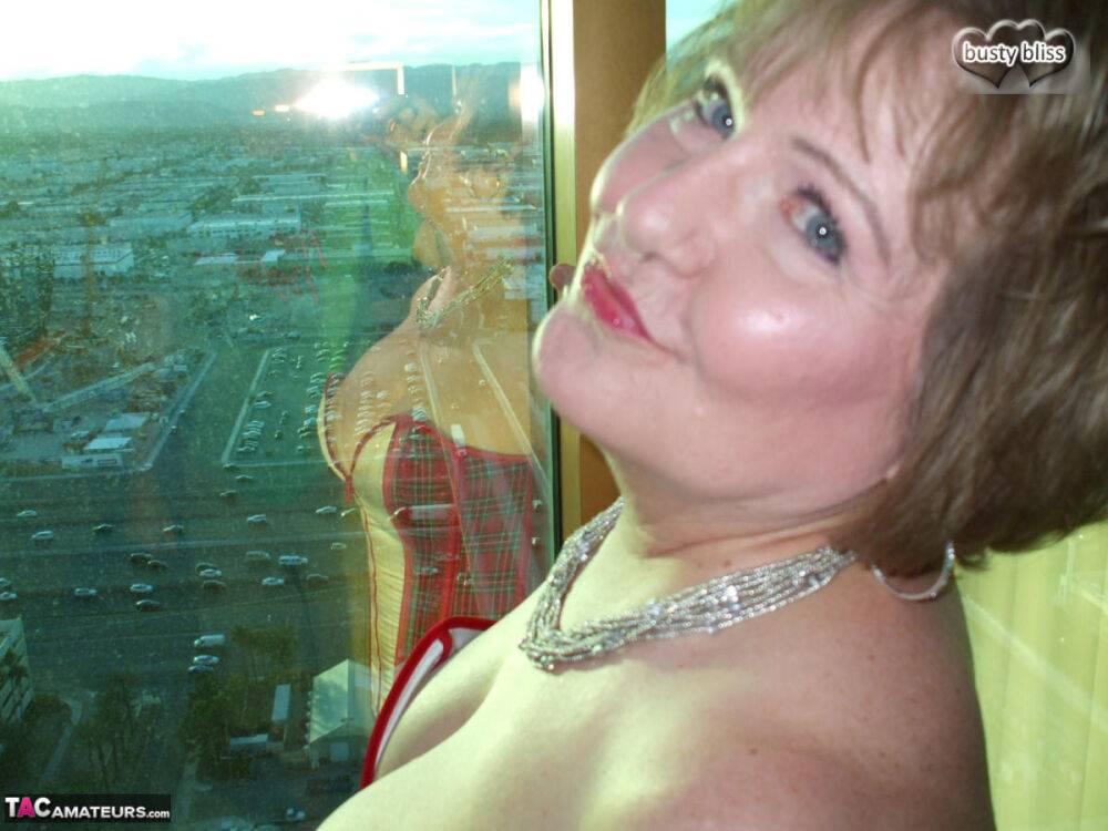 Mature woman Busty Bliss looses her big tits from a corset by her condo window - #8