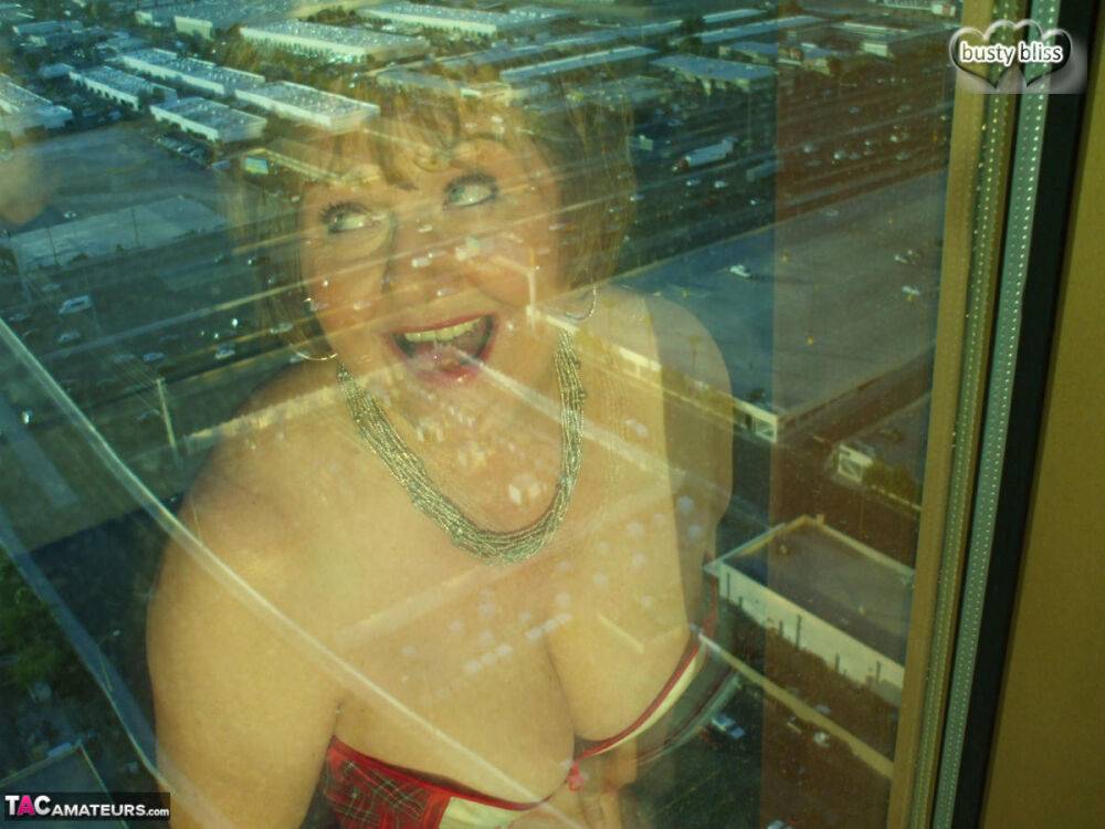 Mature woman Busty Bliss looses her big tits from a corset by her condo window - #15