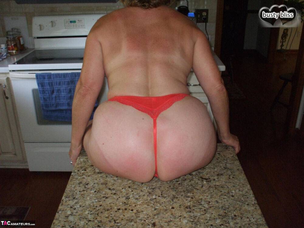 Older amateur Busty Bliss gets naked on a kitchen counter in a thong - #1
