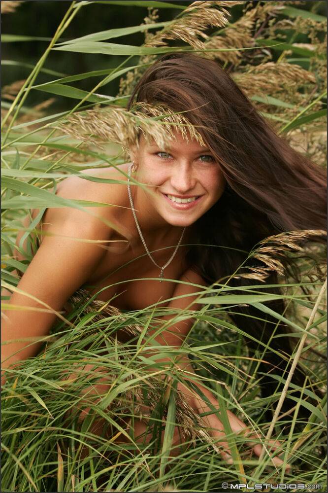 Slender girl models totally naked in the long grasses at a public park - #2