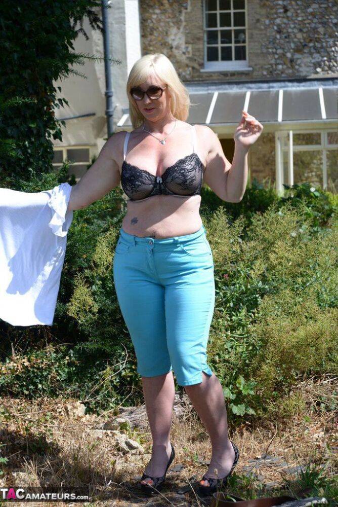 Middle-aged blonde Melody models in a bra while in a backyard - #12