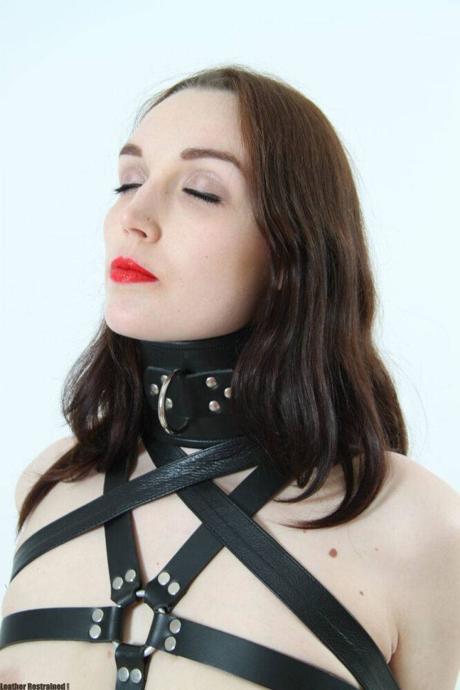 Beautiful girl models leather BDSM attire with her arms restrained behind her - #6