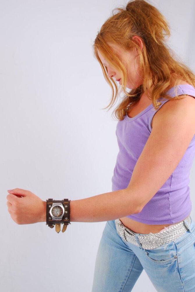 Natural redhead models a large cuff watch in a tank top and faded jeans - #1