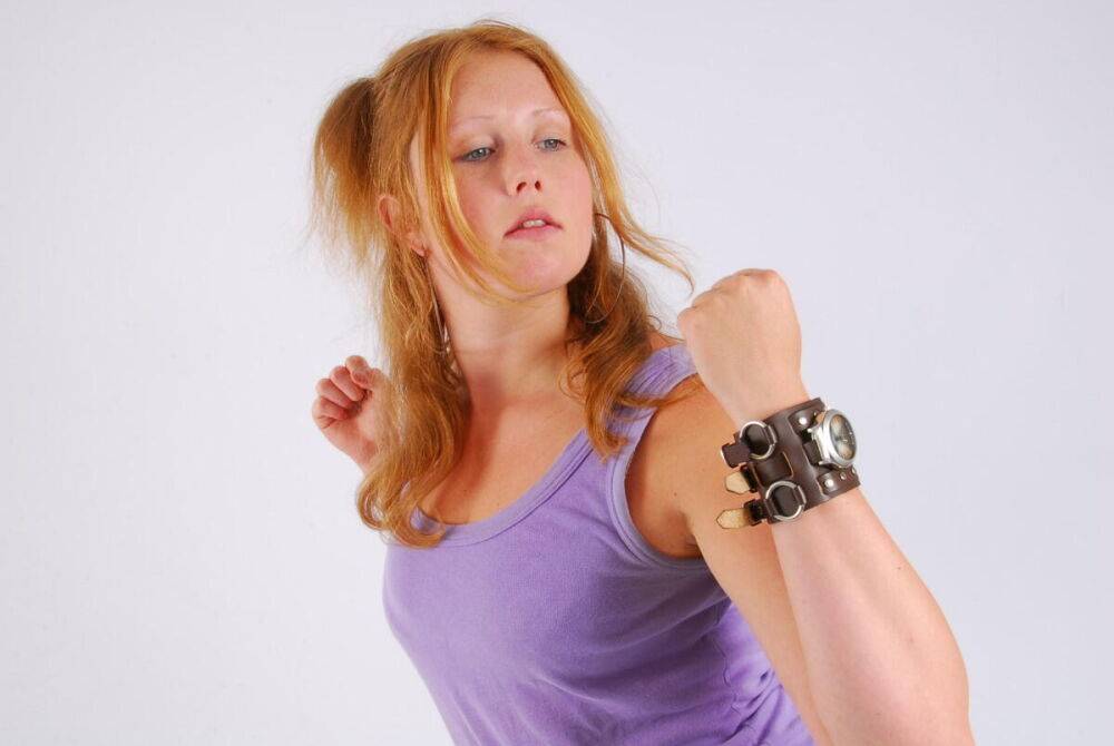 Natural redhead models a large cuff watch in a tank top and faded jeans - #12