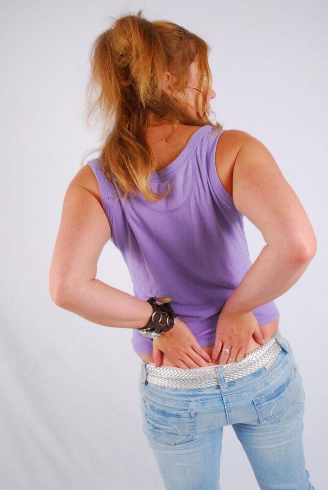 Natural redhead models a large cuff watch in a tank top and faded jeans - #5