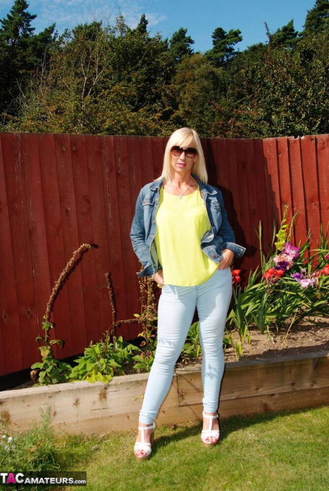 Middle-aged blonde Melody models in a bra and faded jeans in a backyard - #11