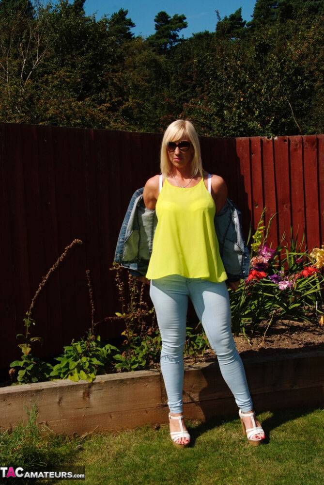 Middle-aged blonde Melody models in a bra and faded jeans in a backyard - #9