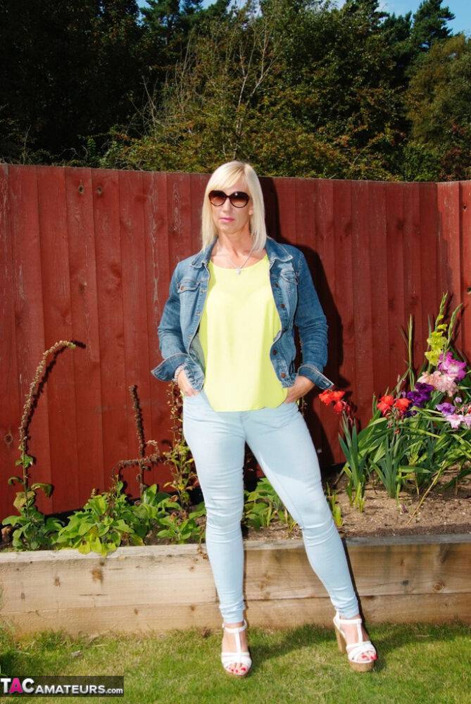 Middle-aged blonde Melody models in a bra and faded jeans in a backyard - #8