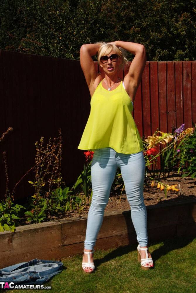 Middle-aged blonde Melody models in a bra and faded jeans in a backyard - #15