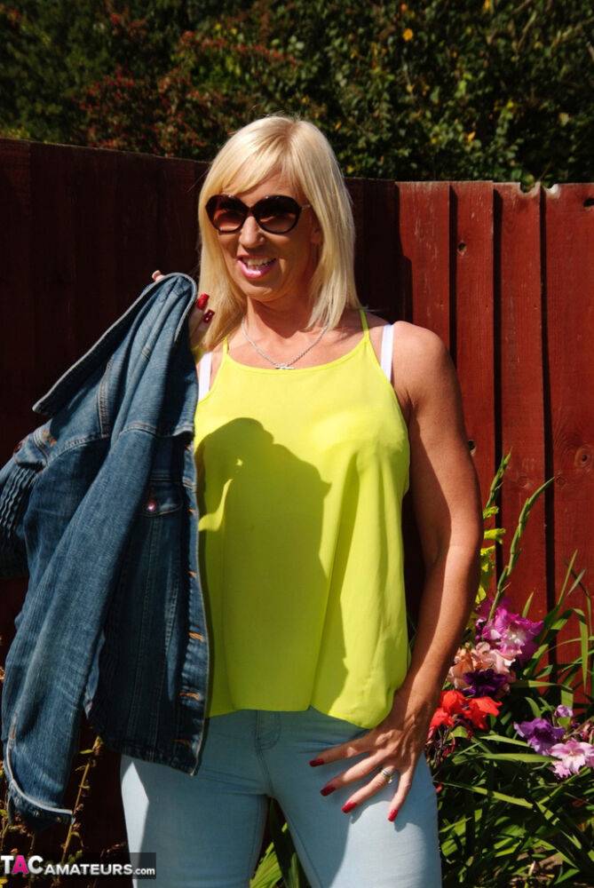 Middle-aged blonde Melody models in a bra and faded jeans in a backyard - #7