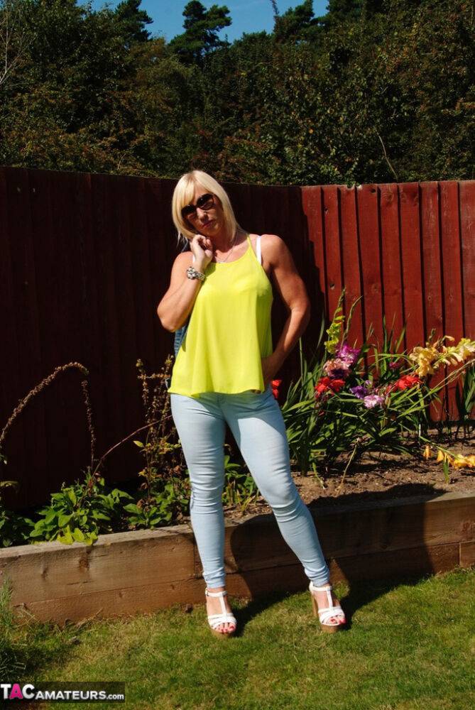 Middle-aged blonde Melody models in a bra and faded jeans in a backyard - #10