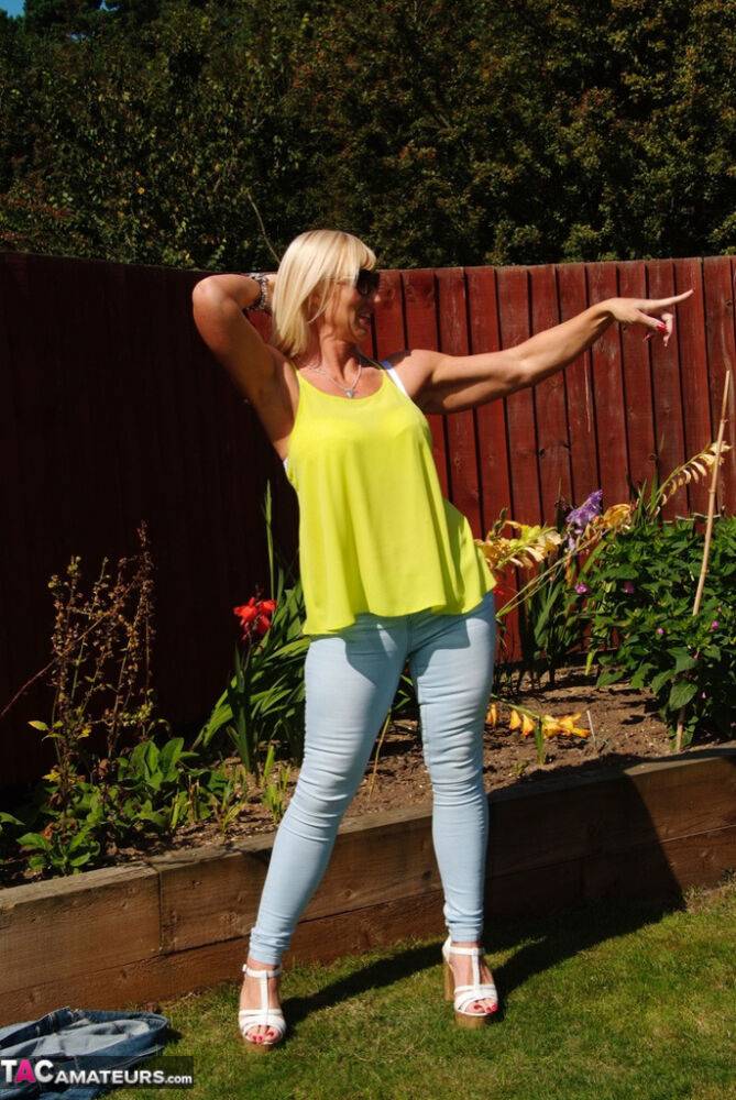 Middle-aged blonde Melody models in a bra and faded jeans in a backyard - #3